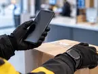 Смартфон в руке курьера, посылка и наручные часы
